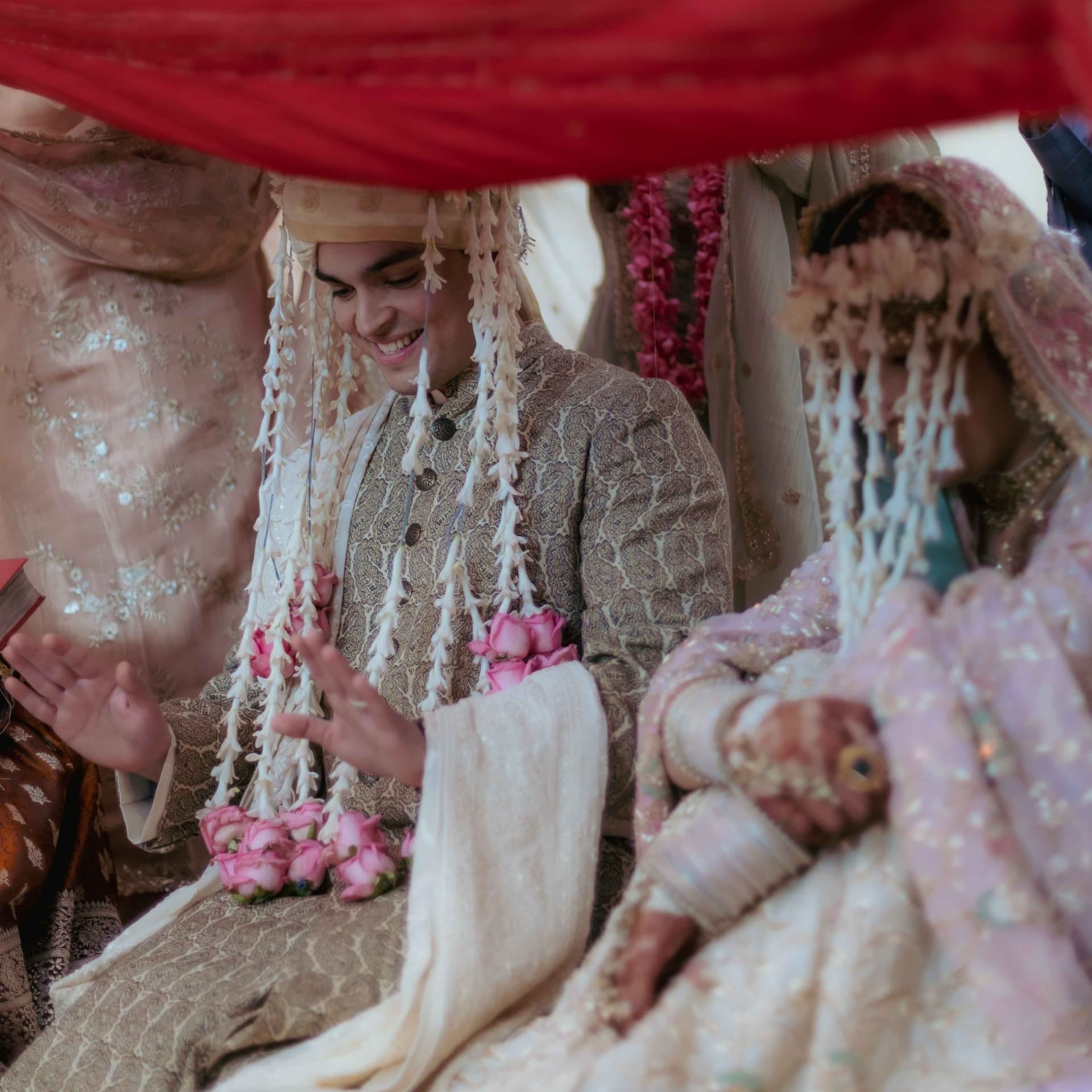 A groom smiling beneath the phera canopy