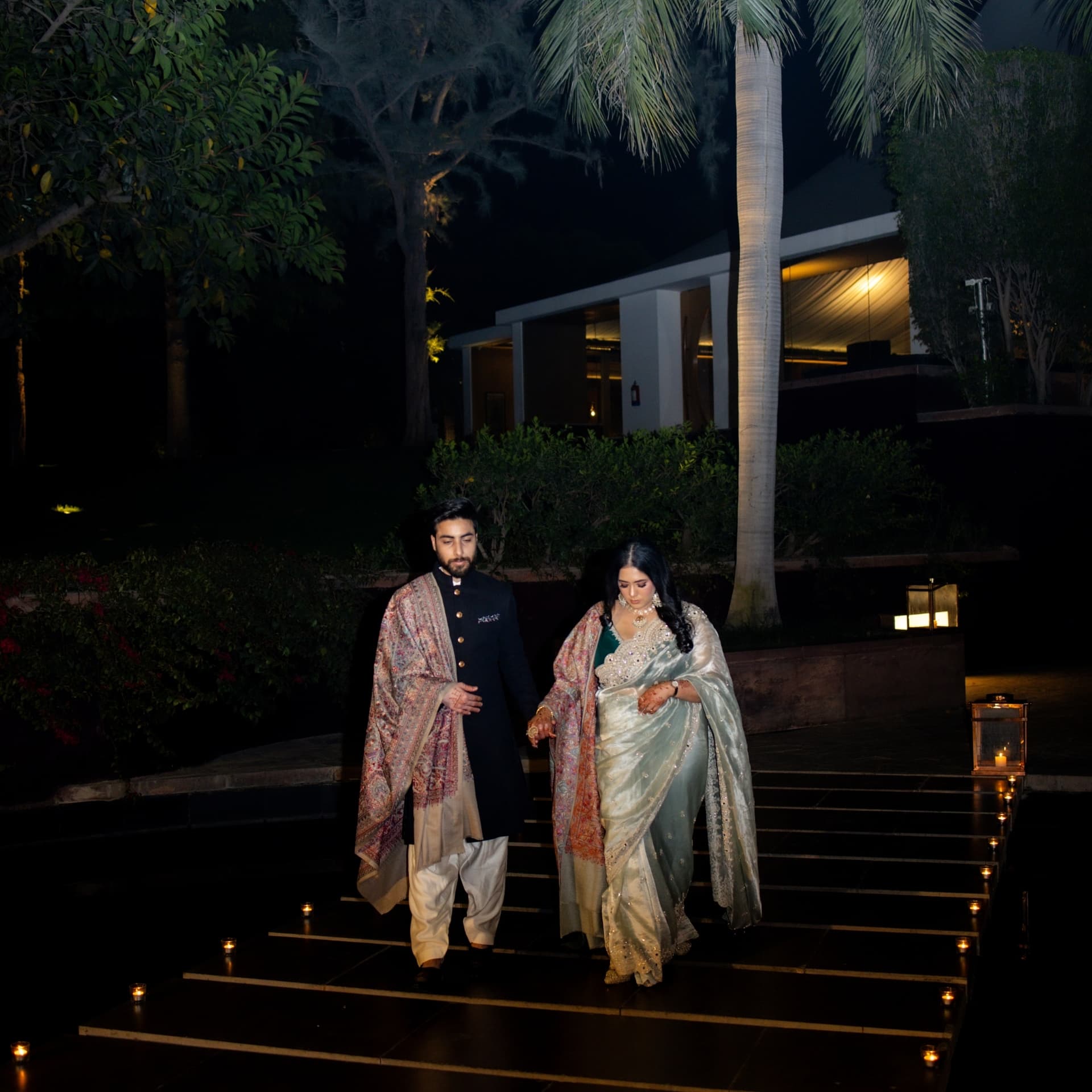 A couple walking candlelit steps at night