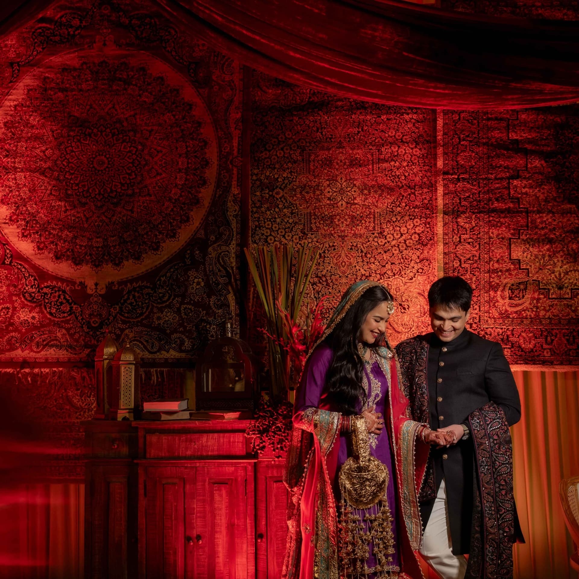 A couple in purple and black before a carpeted wall