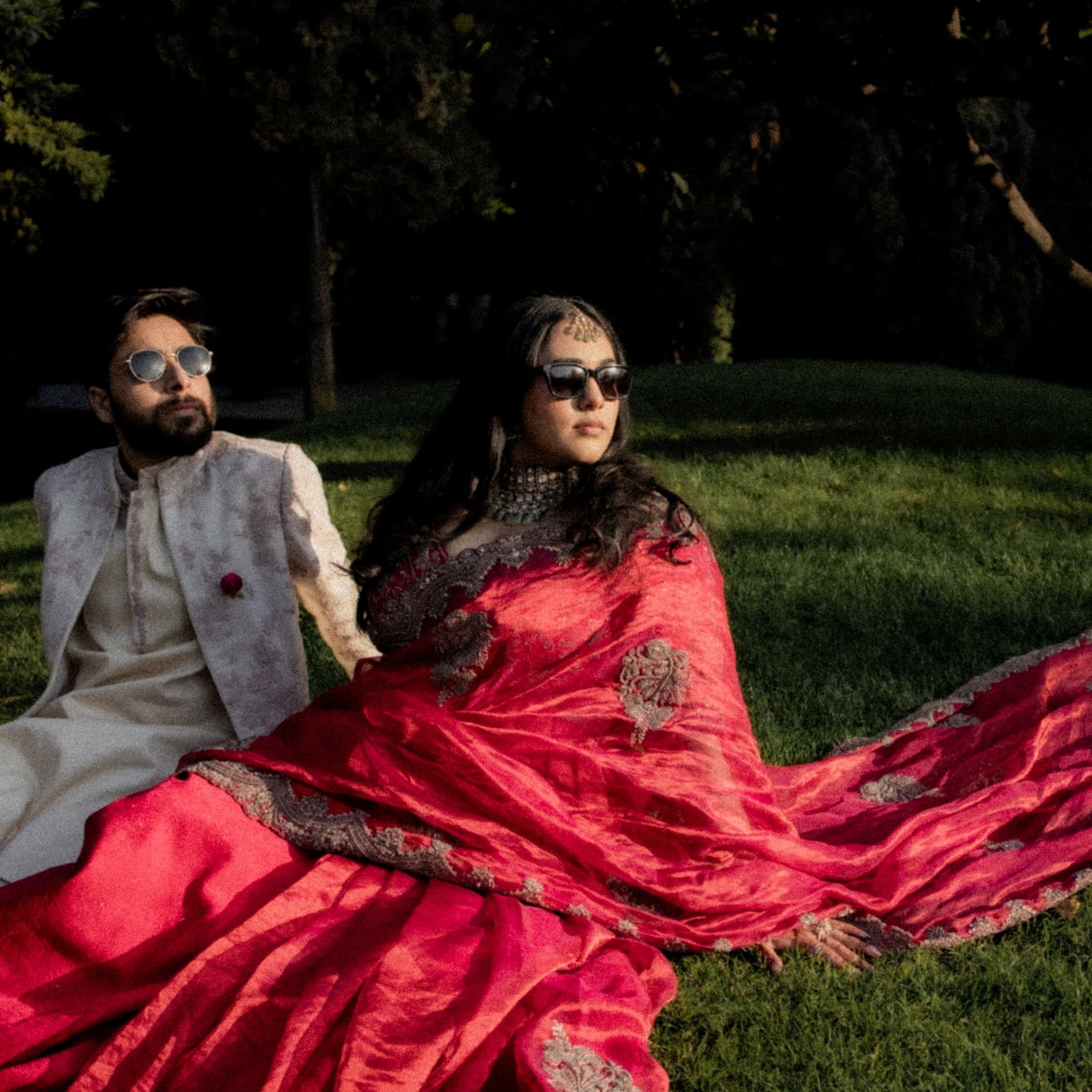 A couple seated on grass in crimson and cream