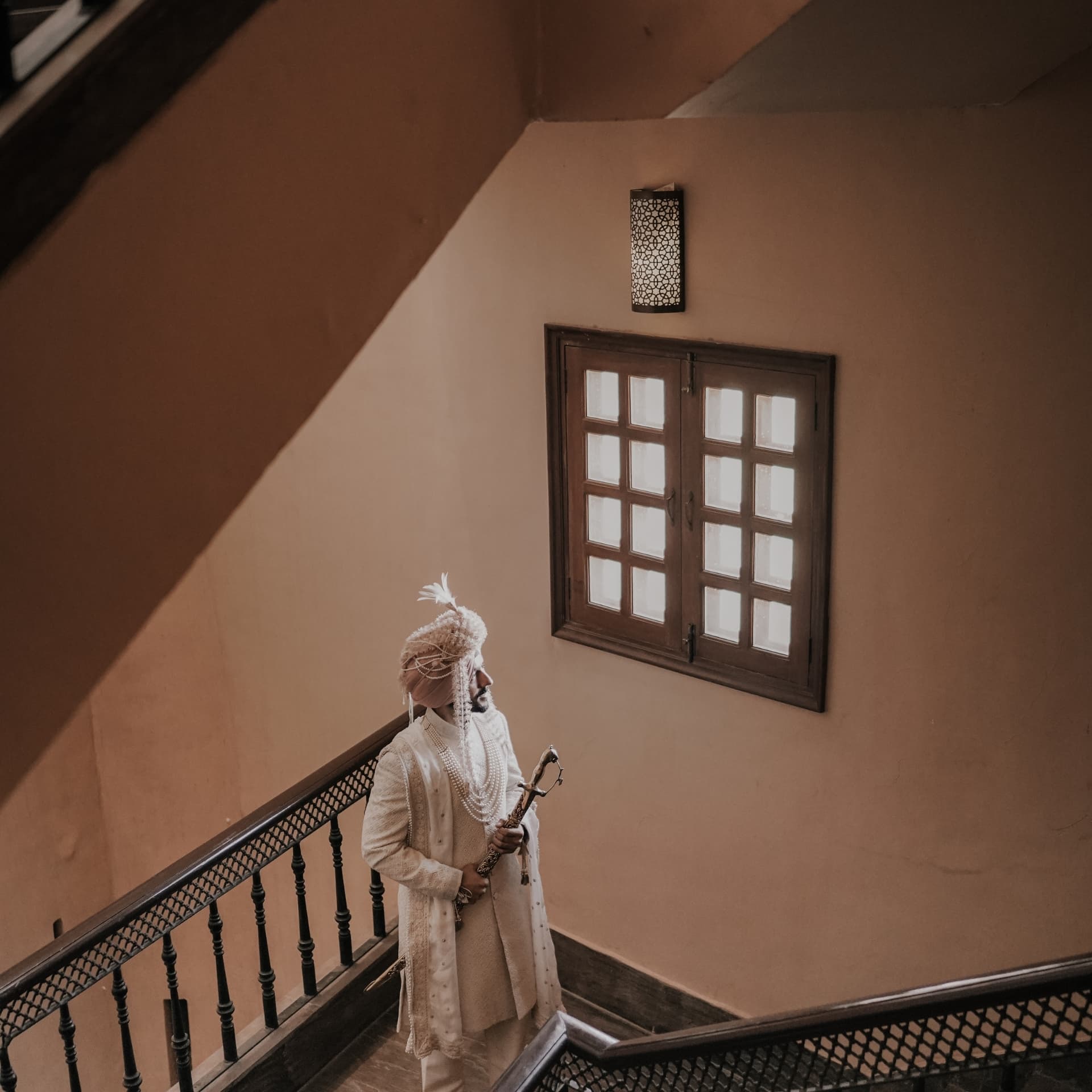 A groom in pearls and turban paused on a stairway