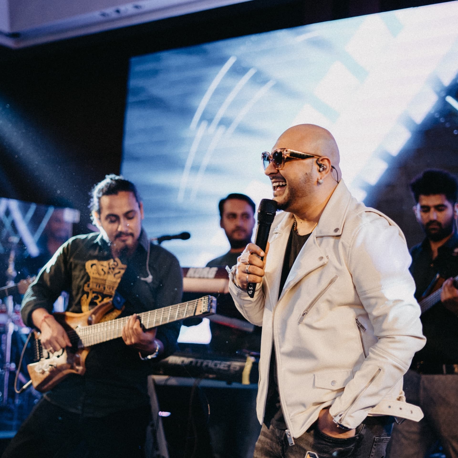 A singer performing with his band in stage light