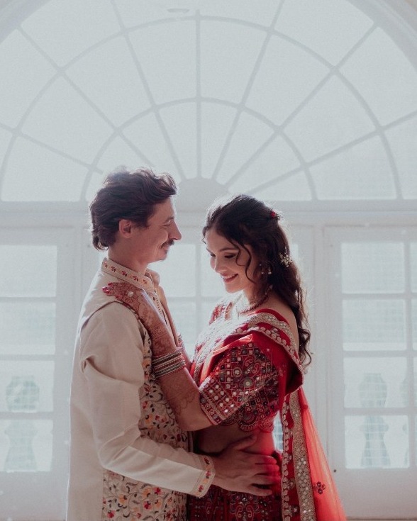 A couple holding each other before a large arched window