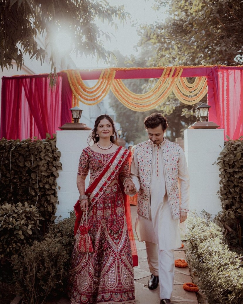 A couple walking hand in hand beneath floral garlands